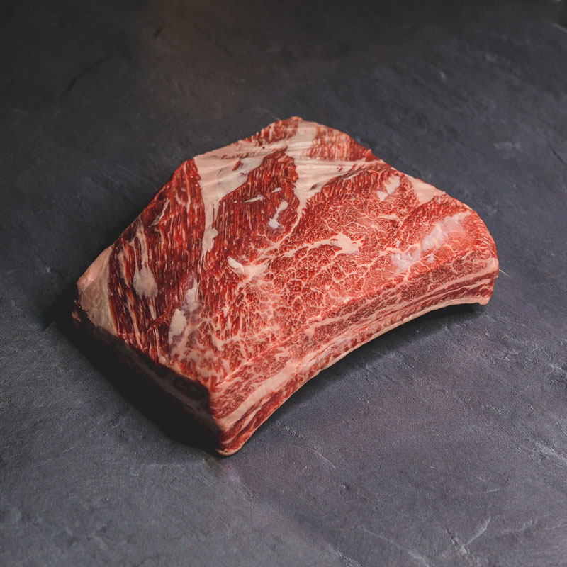 Macelleria Pezzo di carne bovina cruda da barbecue con marmorizzazione evidente su sfondo scuro