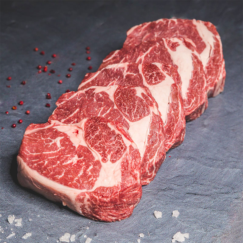 Macelleria selezione di carne bovina su ripiano scuro con bacche di ribes e sale a lato