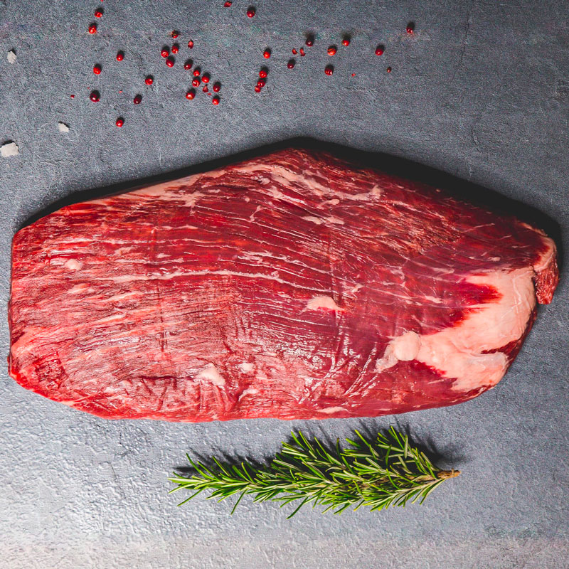 Flank Steak Taglio di flank steak su sfondo scuro con rosmarino a lato e ribes