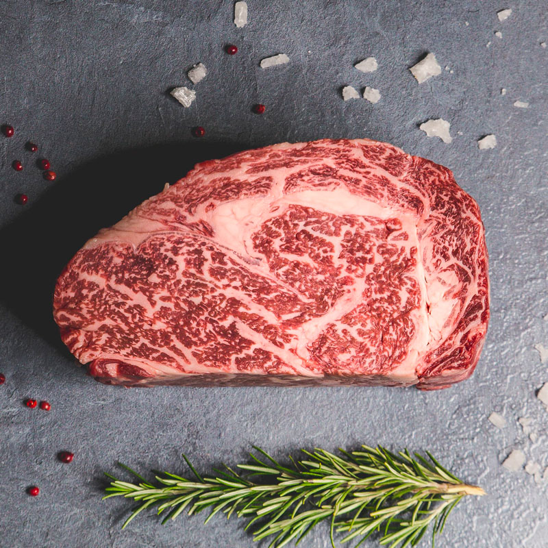 Dry Aged Steak Taglio di dry aged steak su sfondo scuro con rosmarino a lato